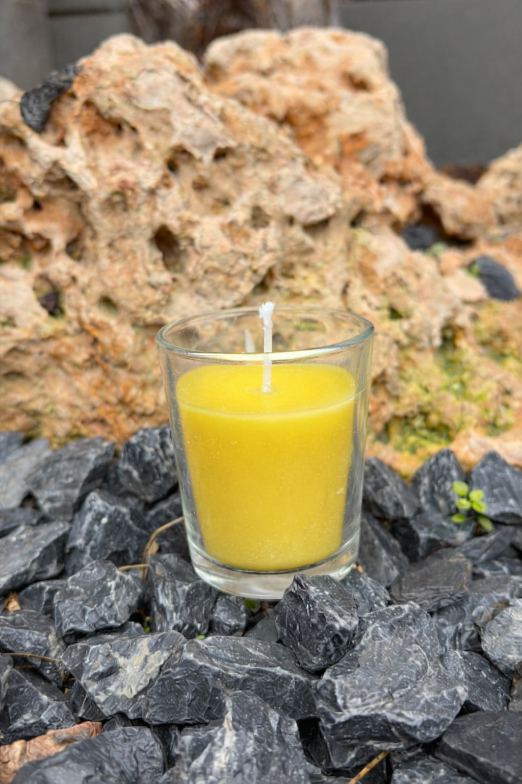 vela amarilla sobre piedras oscuras